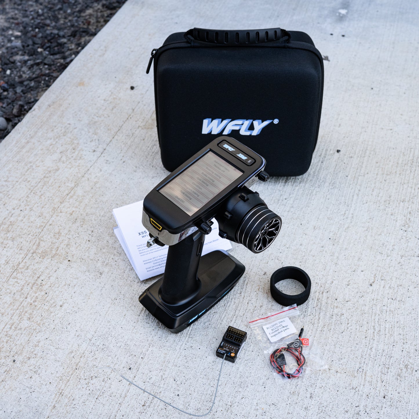 WFLY X9S 2.4GHz digital RC transmitter with RG209S receiver, wires, and accessories displayed in front of branded carrying case.