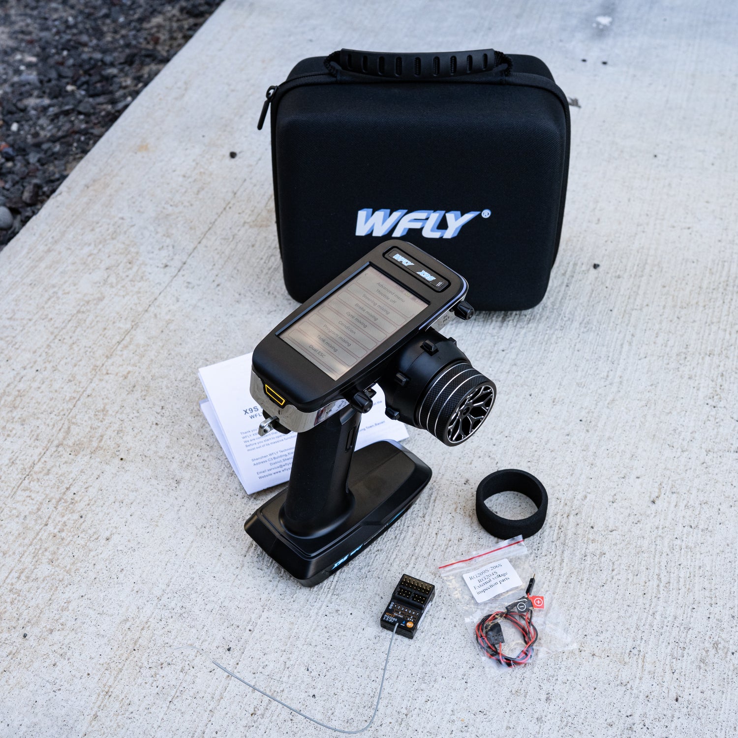 WFLY X9S 2.4GHz digital RC transmitter with RG209S receiver, wires, and accessories displayed in front of branded carrying case.