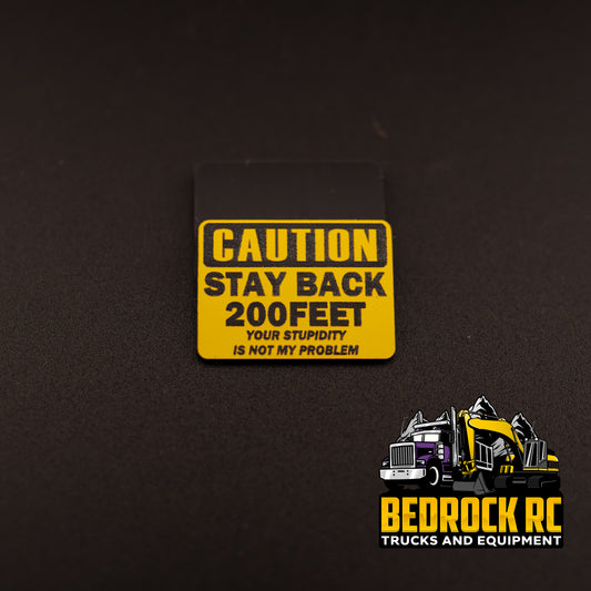 Bedrock Built Caution – Stay Back 200 Feet – Your Stupidity Is Not My Problem sign for 1/14 scale RC trucks, laser-etched hard plastic 31.5 × 23 mm, built in-house by Bedrock RC.